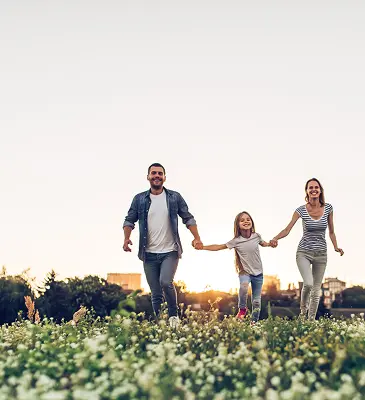 A family frolicking in a field full of flowers.