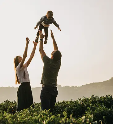 Family frolicking in the field of flowers playing with a young child after a long day of asset management solutions.
